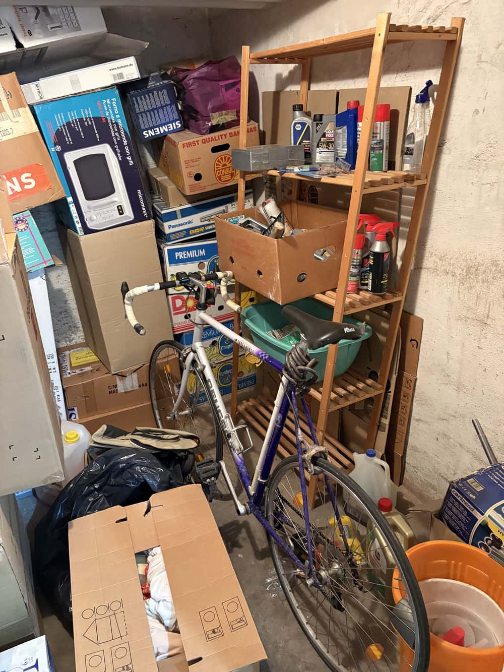Kellerabteil vor der Entrümpelung, Regale und Fahrrad bis unter die Decke