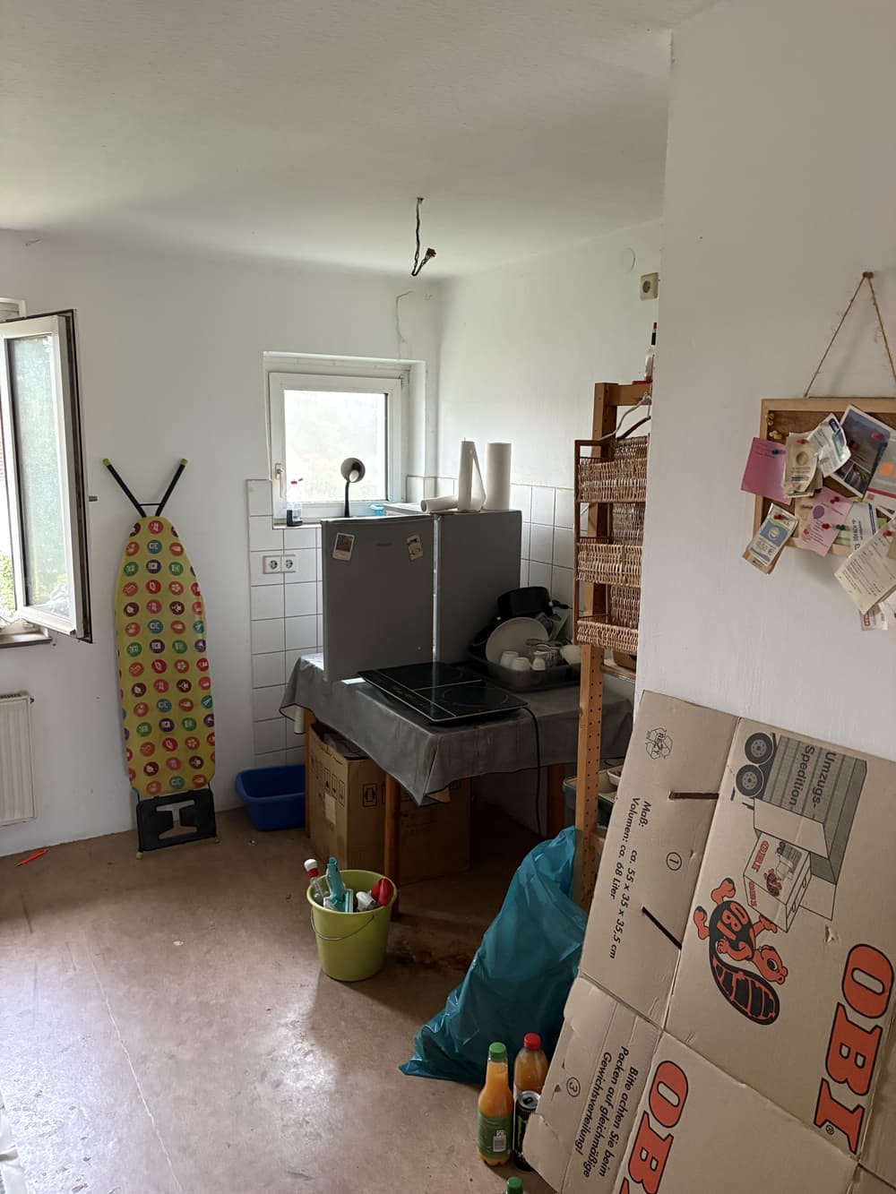 Küche vor der Haushaltsauflösung mit Geräten, Kartons und Bügelbrett