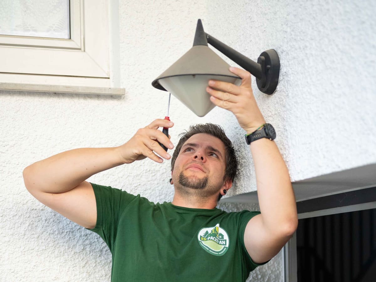 Marco Kusch wartet eine Außenleuchte an einer Hauswand