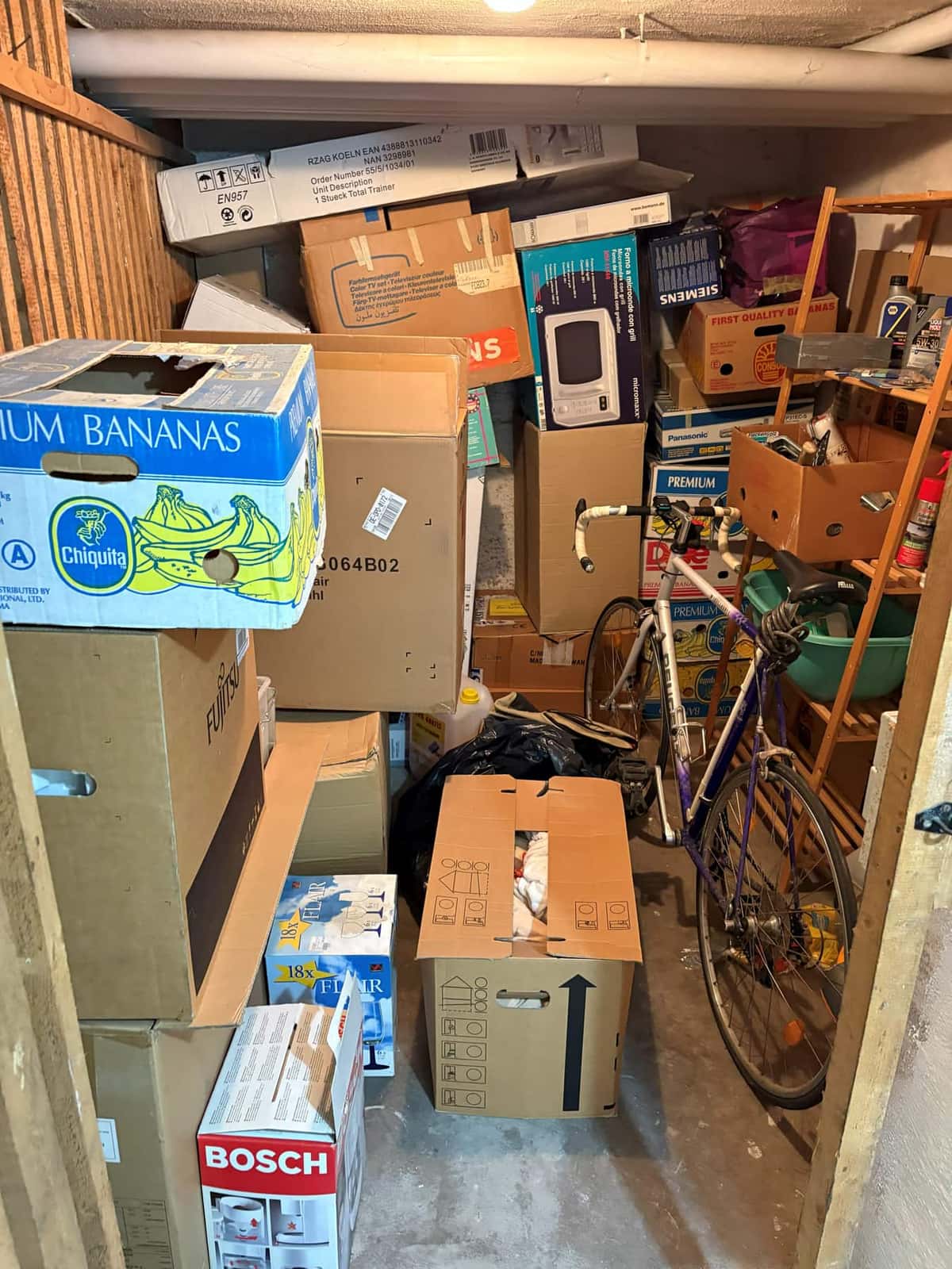 Kellerabteil vor der Räumung, bis unter die Decke mit Kartons, Fahrrad und Regal gefüllt