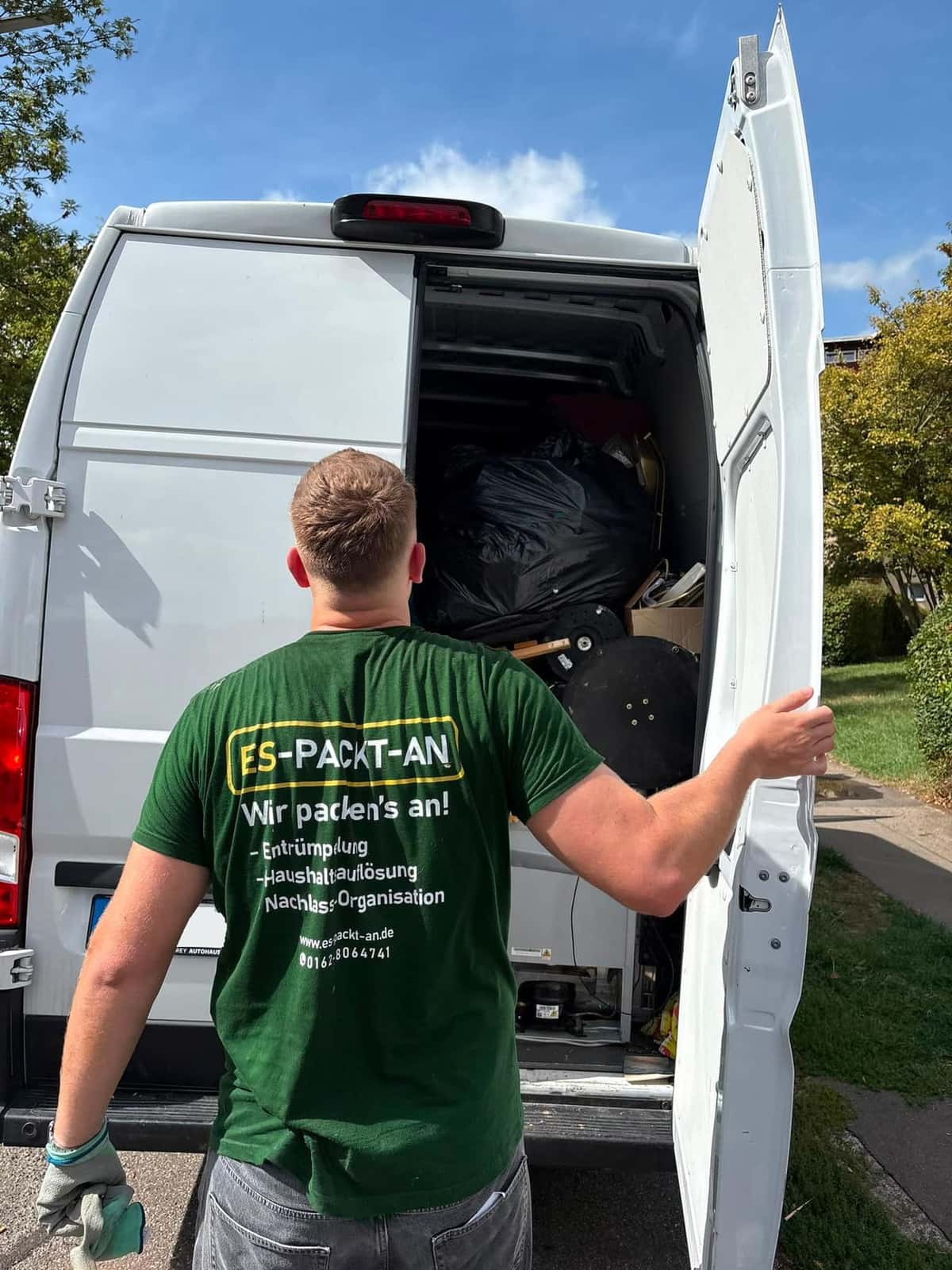 Mitarbeiter von ES-PACKT-AN im Firmenshirt öffnet den beladenen Transporter